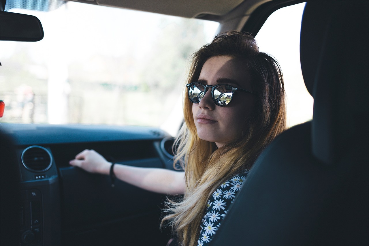 A woman in the passenger seat of a car wearing sunglasses