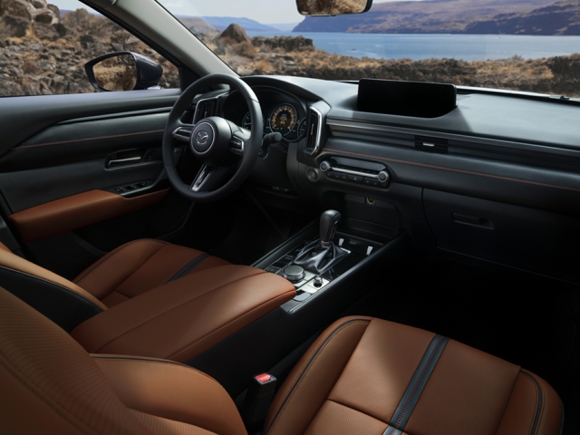 The passenger and driver's seat of Mazda facing a body of water and mountains
