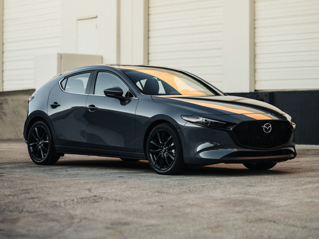 A dark gray Mazda parked outside of a building